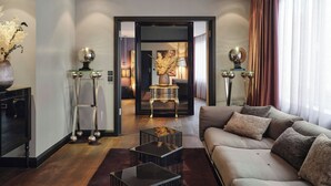 Una sala de estar moderna con un sofá, una mesa de centro y lámparas decorativas. Hay una puerta que conduce a otra habitación.