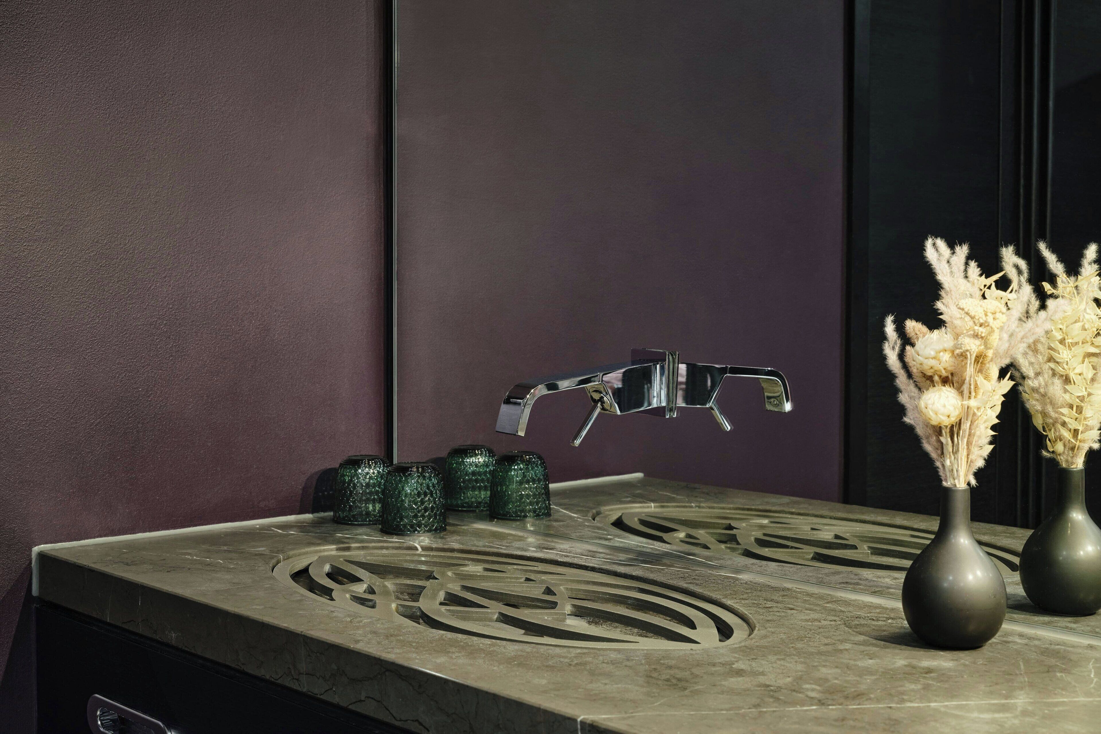 A modern bathroom with a marble sink, a faucet, and decorative vases.