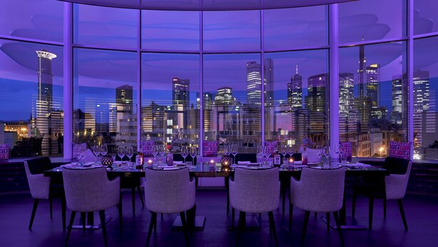 Comedor con vista al horizonte de la ciudad, sillas modernas y una mesa lista para comer.