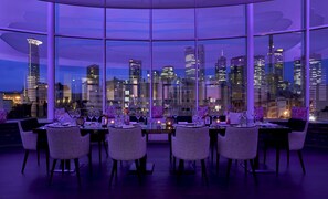 A dining area with a city skyline view, modern chairs, and a table set for a meal. - Roomers Frankfurt Central, Autograph Collection (Frankfurt)