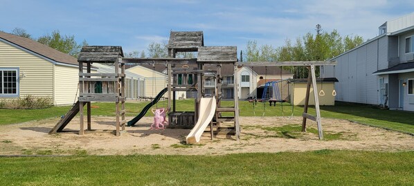 A playground with a slide and swings, surrounded by houses. - Mackinaw Budget Inn (Mackinaw City)
