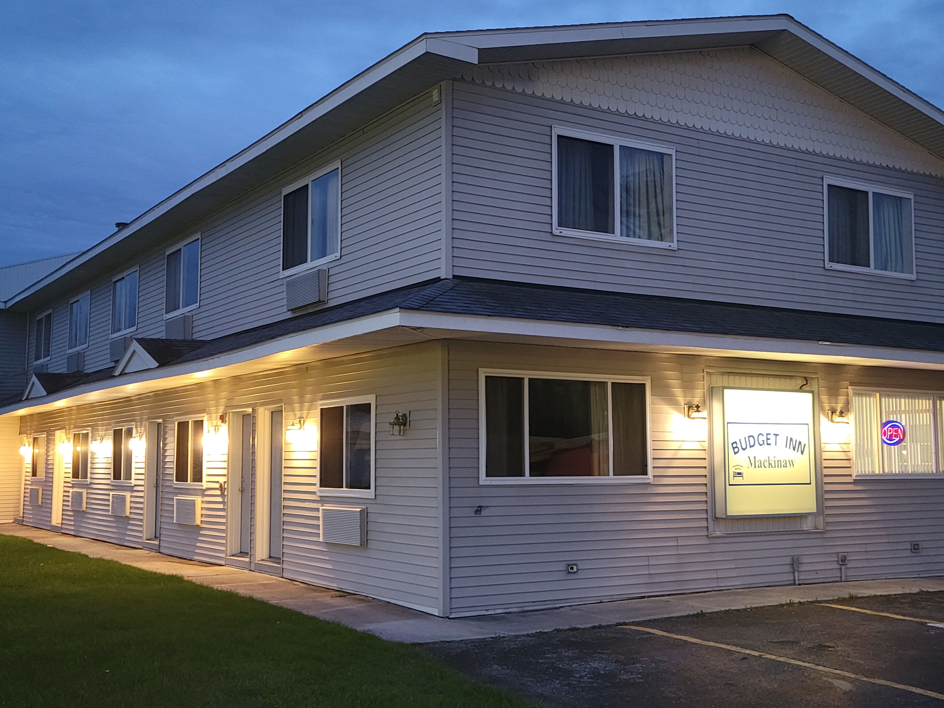 Een motel met twee verdiepingen, met een bord waarop 'Budget Inn Mackinaw' staat.