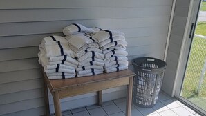 Een overdekte veranda met een houten bank en een stapel opgevouwen handdoeken.