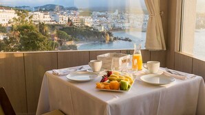 A table set with breakfast items and a view of a coastal town. - Hotel Sant Roc (Palafrugell)