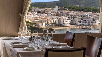 A table set for dining with a view of a coastal town.