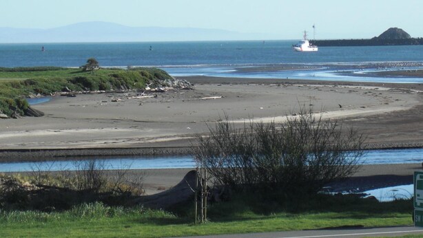 A coastal landscape with a sandy beach, a lighthouse, and a body of water. - Front Street Inn (Crescent City)