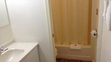 A bathroom with a white sink, a shower with a beige curtain, and a toilet.