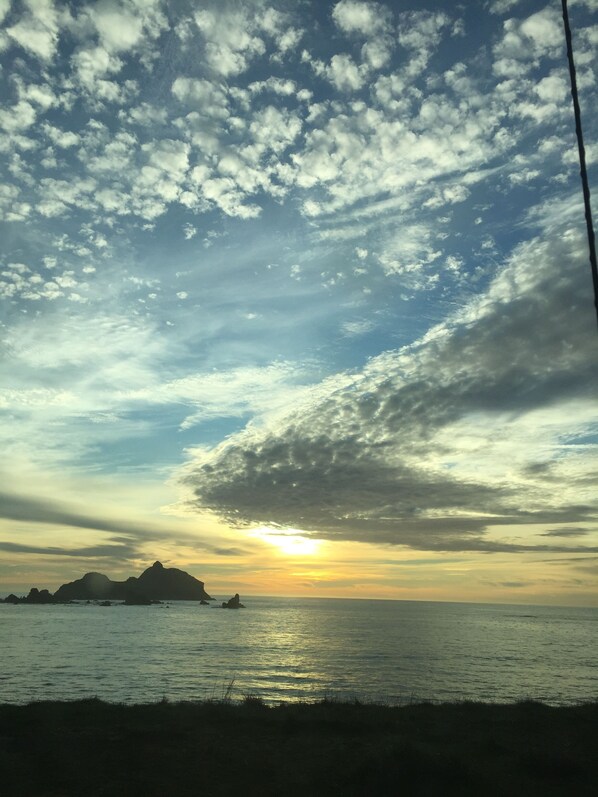 A coastal sunset with a clear sky and distant landforms.