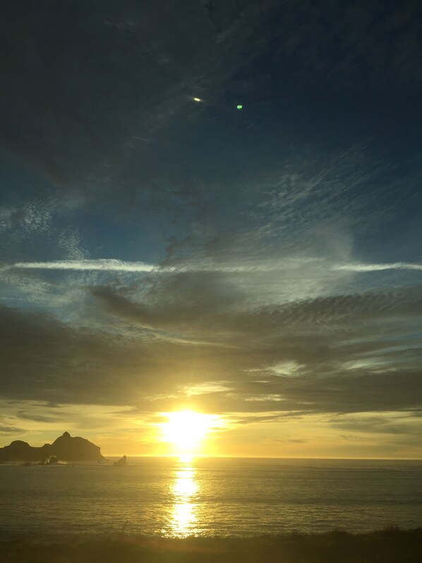 A sunset over the ocean with clouds and a distant landmass.