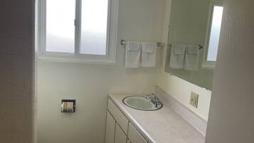 A small bathroom with a window, a sink, and a mirror.