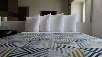 A hotel room with a bed, a nightstand, a telephone, and a mirror.