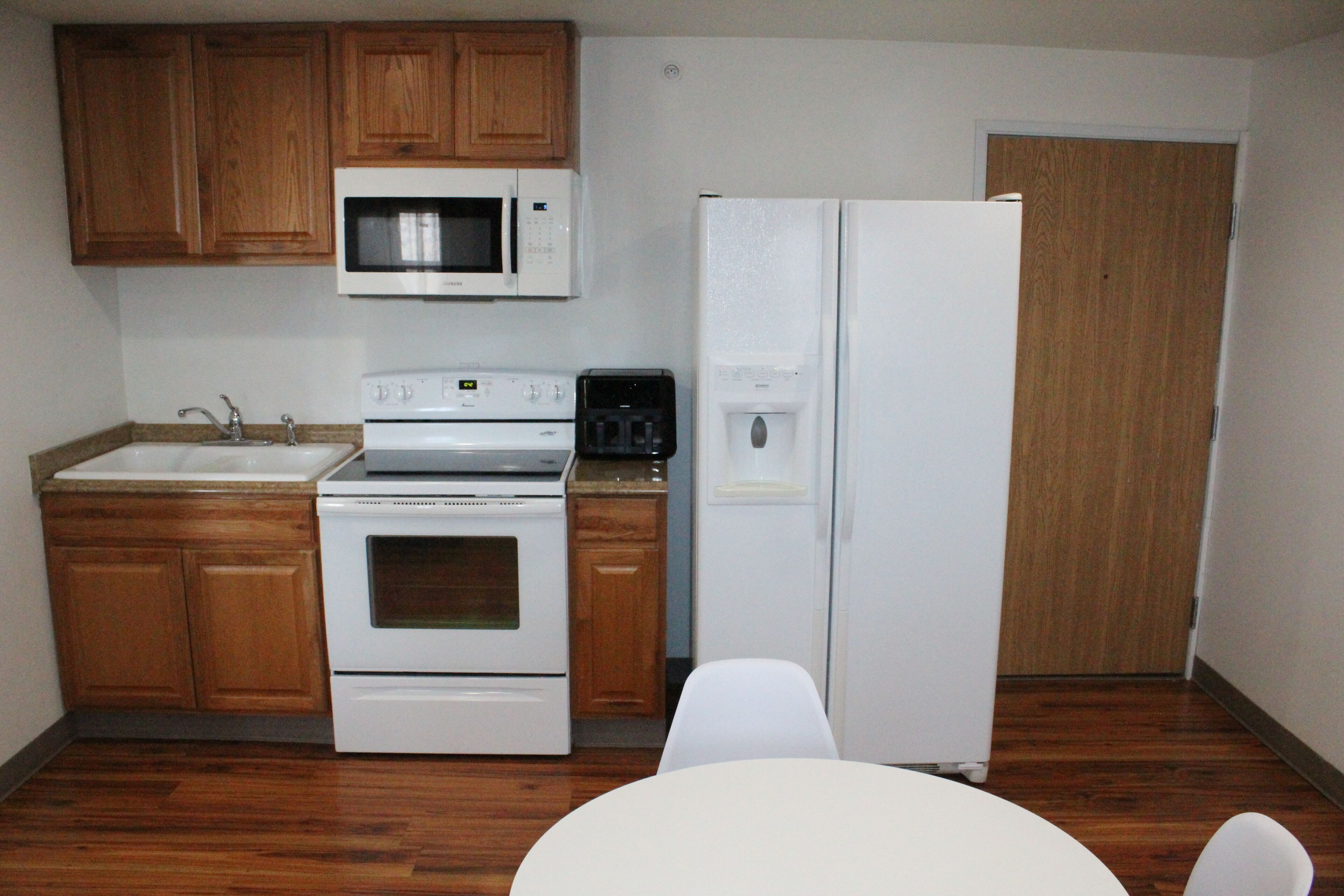 A kitchen with wooden cabinets, a microwave, a stove, a refrigerator, and a sink.