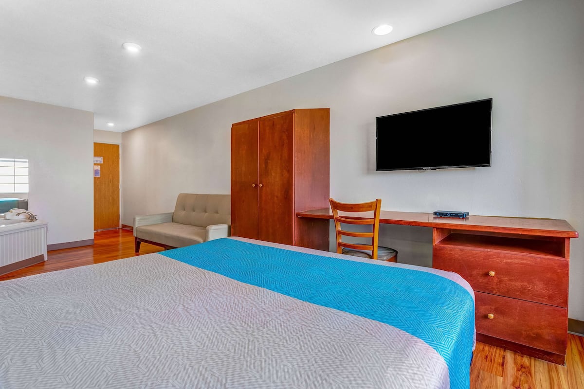 Ein Schlafzimmer mit Bett, Schreibtisch, Stuhl, Kleiderschrank und Fernseher.