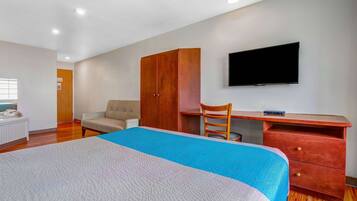 A bedroom with a bed, a desk, a chair, a wardrobe, and a TV.