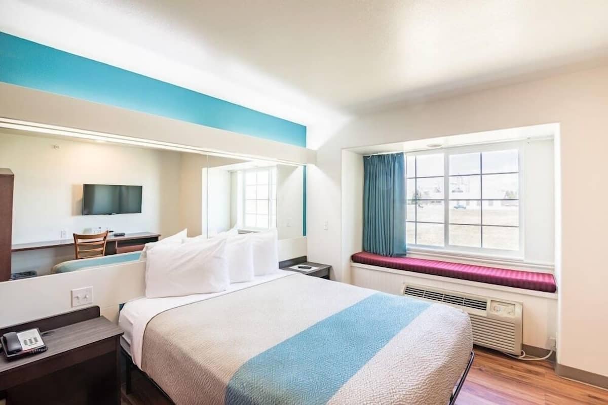 Ein Hotelzimmer mit Bett, Schreibtisch, Stuhl, Fernseher, einem Fenster mit Blick und einer fest eingebauten Sitzbank.