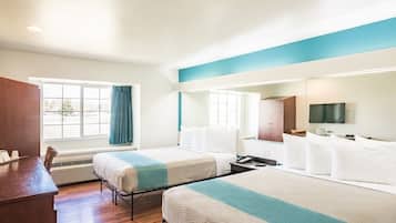 A hotel room with two beds, a desk, a TV, and a window with curtains.