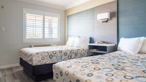 A hotel room with two beds, a window with blinds, a bedside table, and a wall-mounted air conditioner. - Solaire Inn & Suites (Santa Maria)