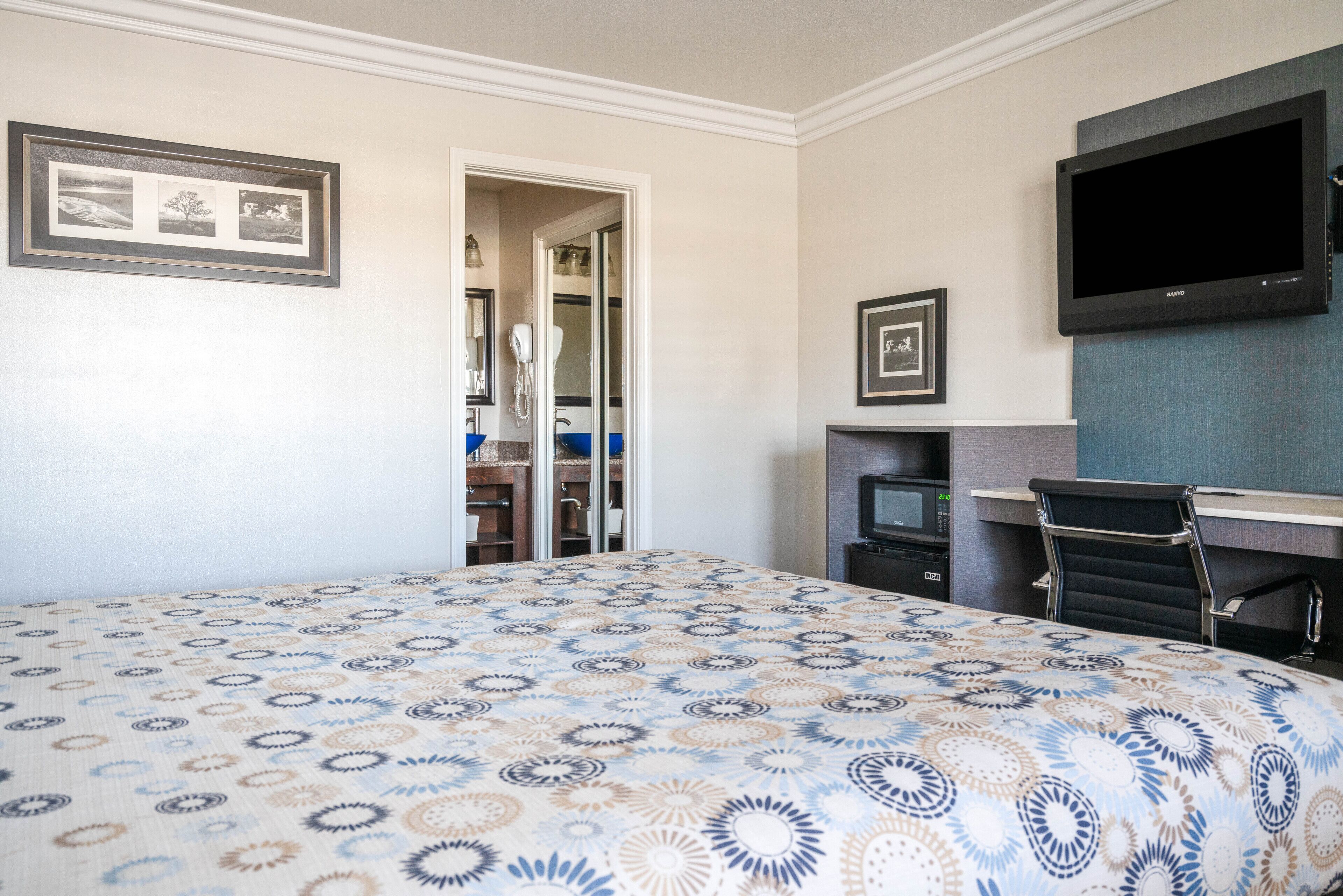 Ein Hotelzimmer mit Bett, Fernseher, Schreibtisch und Kleiderschrank.