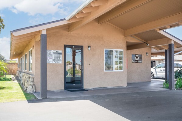 A building with a covered entrance, a glass door, and a sign indicating a recycling center.