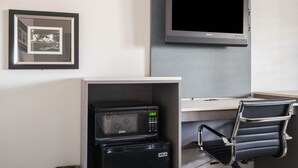 A kitchenette with a microwave, a small refrigerator, a chair, and a flat-screen TV mounted on the wall. - Solaire Inn & Suites (Santa Maria)