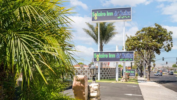 A sign for Solaire Inn & Suites with a clear view of the surrounding palm trees and a street in the background. - Solaire Inn & Suites (Santa Maria)