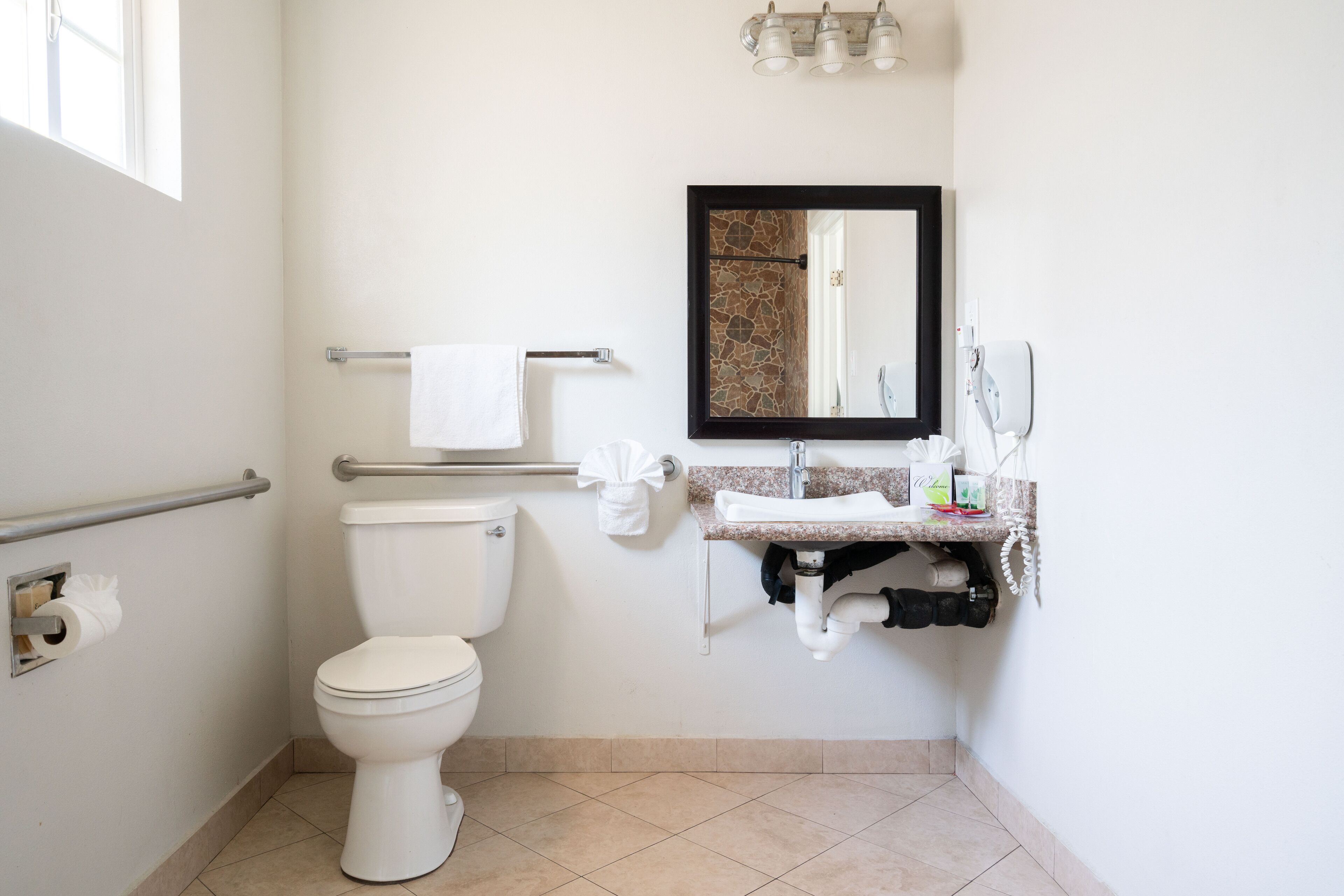 Een badkamer met toilet, wastafel, spiegel, handdoekrek en handdroger.
