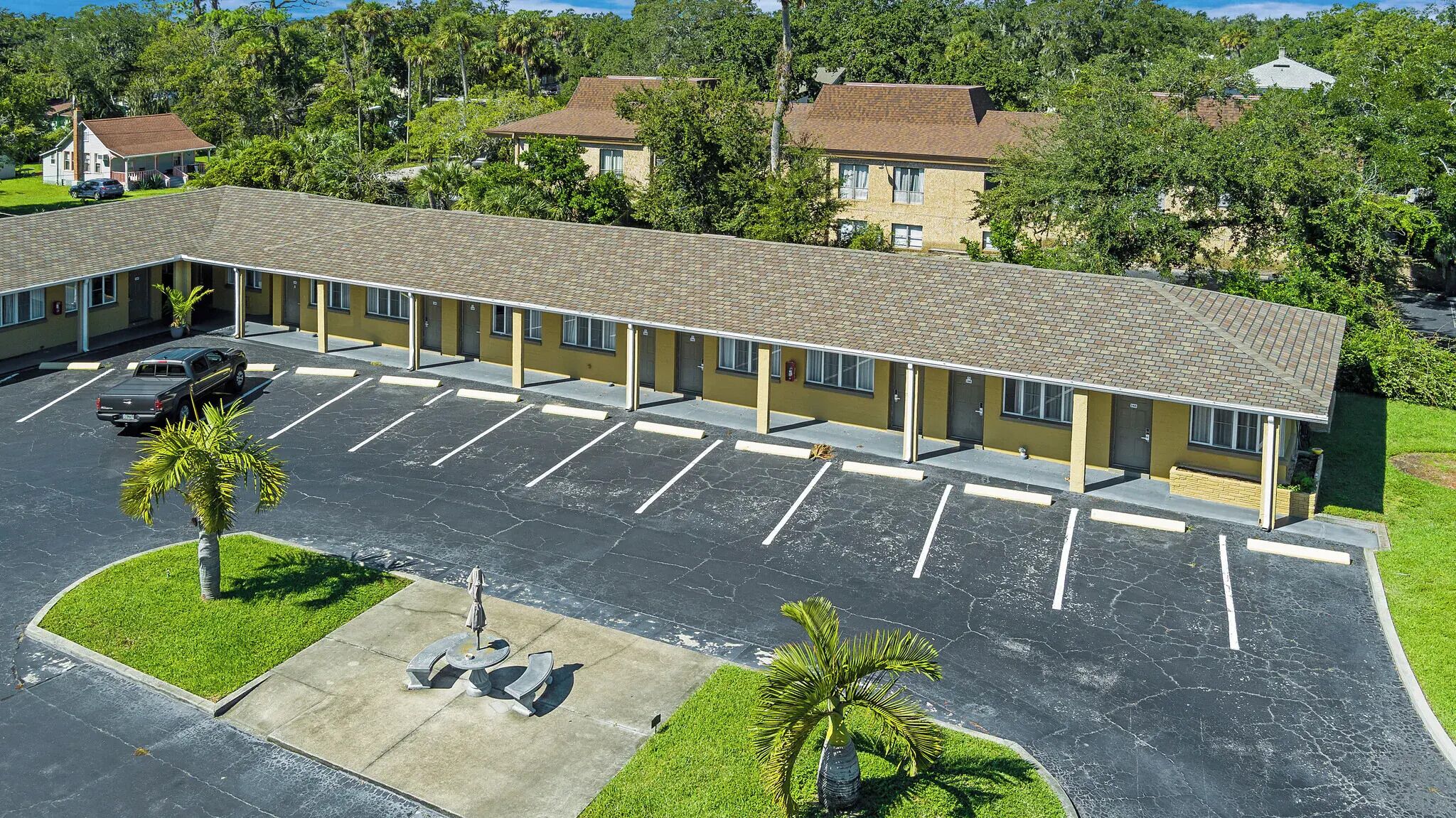 A motel with a parking lot, a covered walkway, and a small garden area.