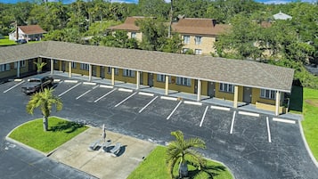 A motel with a parking lot, a covered walkway, and a small garden area.