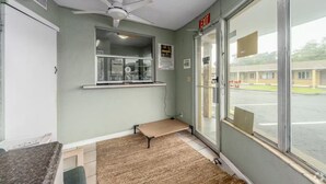 Ein Zimmer mit Deckenventilator, einem Fenster mit Außenblick, einer Bank und einem Ausgangsschild.