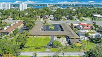 Un quartier résidentiel avec un bâtiment central entouré de verdure et, au loin, un port de plaisance.