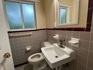 A bathroom with a toilet, sink, and window. - Lumina Motel (Daytona Beach)