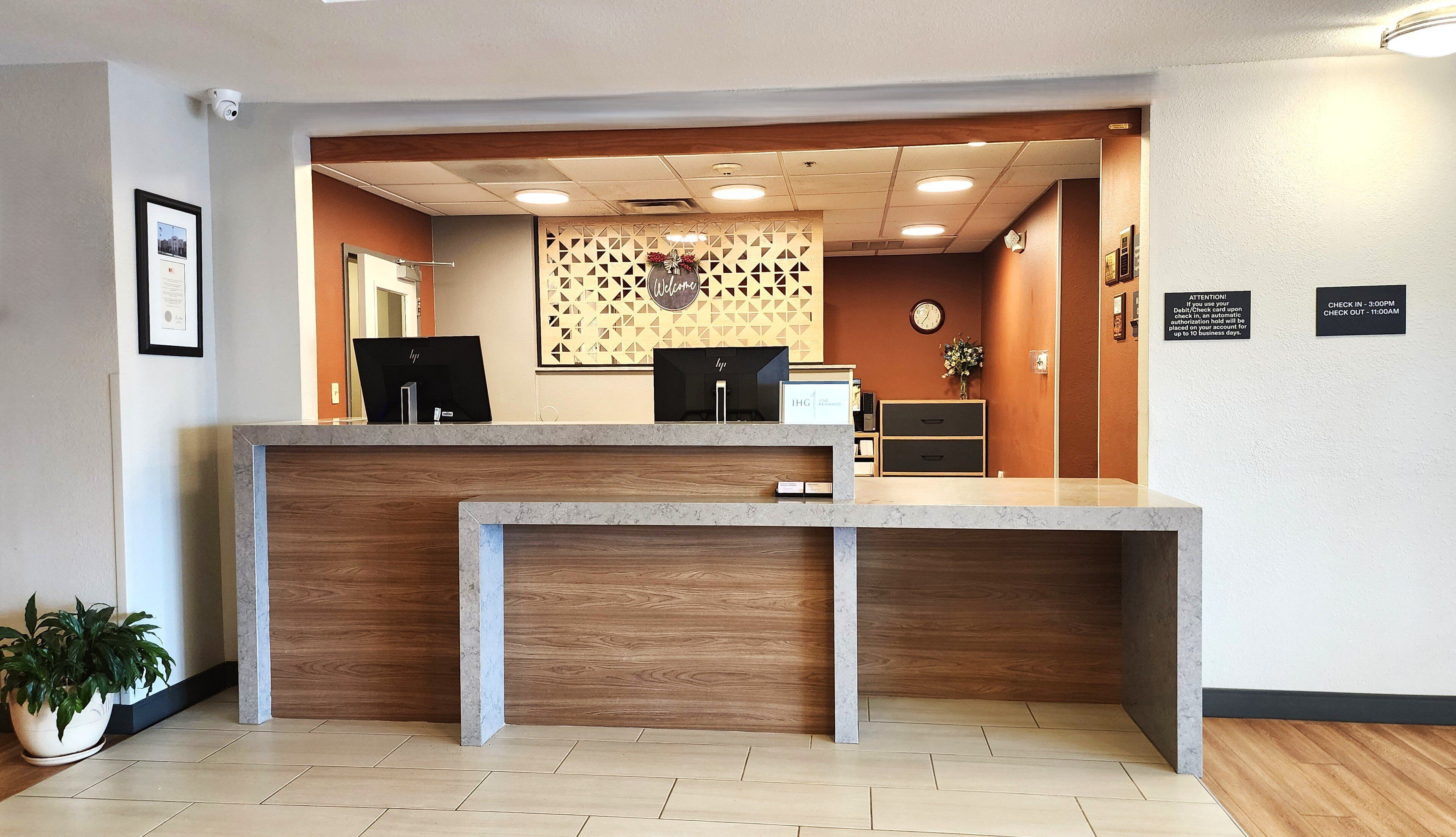 A reception desk with a wooden counter, a computer, and a clock on the wall.