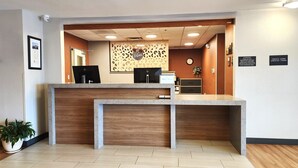 A reception desk with a wooden counter, a computer, and a clock on the wall. - Candlewood Suites Sheridan by IHG (Sheridan)