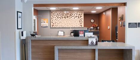 Un comptoir d’accueil avec un revêtement en bois, une horloge et un mur décoré en arrière-plan.