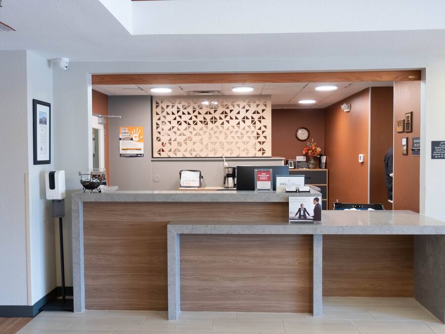 A reception desk with a wooden finish, a clock, and a patterned wall in the background.