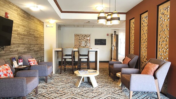 A hotel lobby with a reception desk, seating area, and a television. - Candlewood Suites Sheridan by IHG (Sheridan)