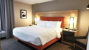 A hotel room with a large bed, two bedside tables, a chair, a nightstand with a phone, and a wall-mounted picture. - Candlewood Suites Sheridan by IHG (Sheridan)