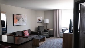 A hotel room with a sofa, armchair, coffee table, lamp, and a television. - Candlewood Suites Sheridan by IHG (Sheridan)