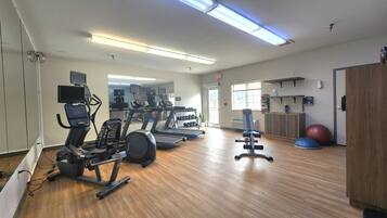 A gym with treadmills, elliptical machines, and free weights.