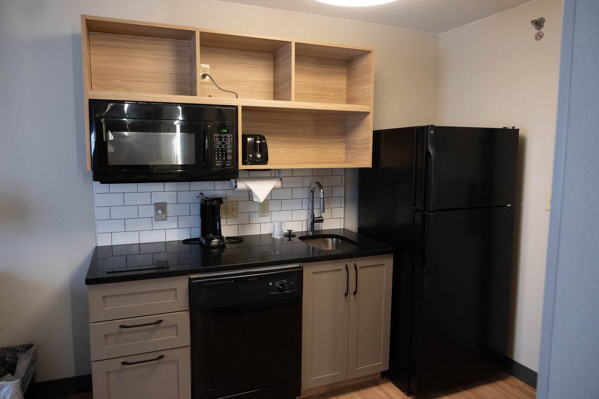 A compact kitchen with a black refrigerator, a microwave, and a coffee maker on the countertop.