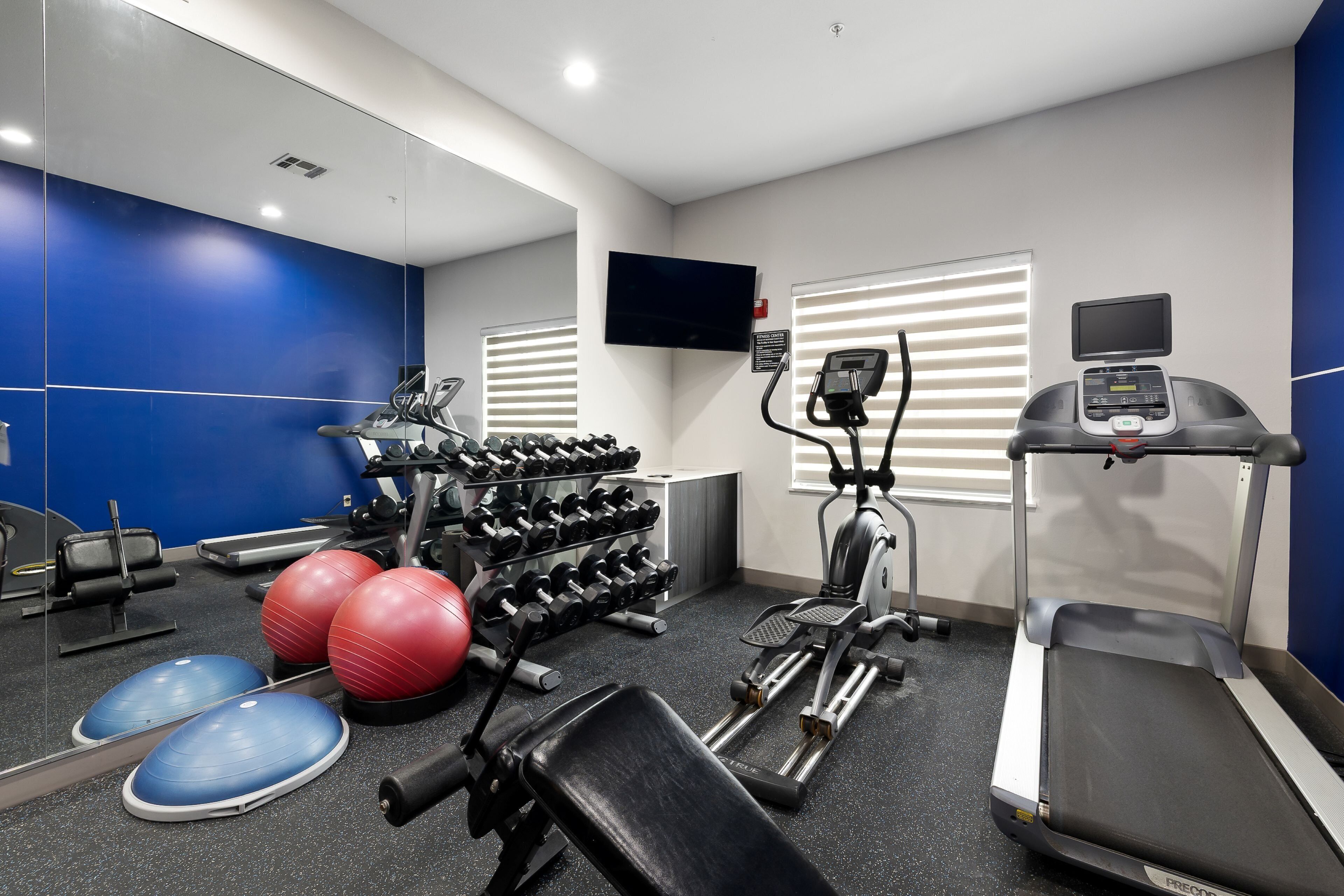 Ein Fitnessstudio mit Laufbändern, Crosstrainern, Kurzhanteln und Trainingsbällen.