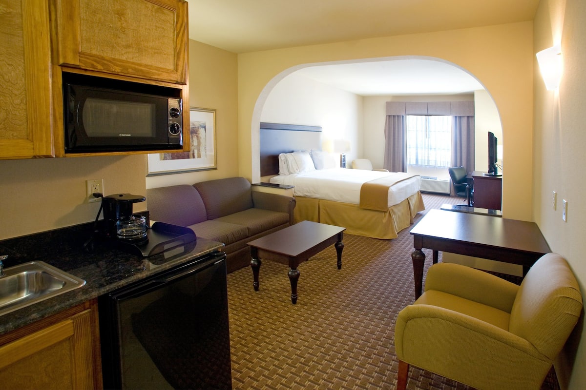 Une chambre d’hôtel équipée d’une kitchenette, d’un canapé, d’un lit et d’un bureau.