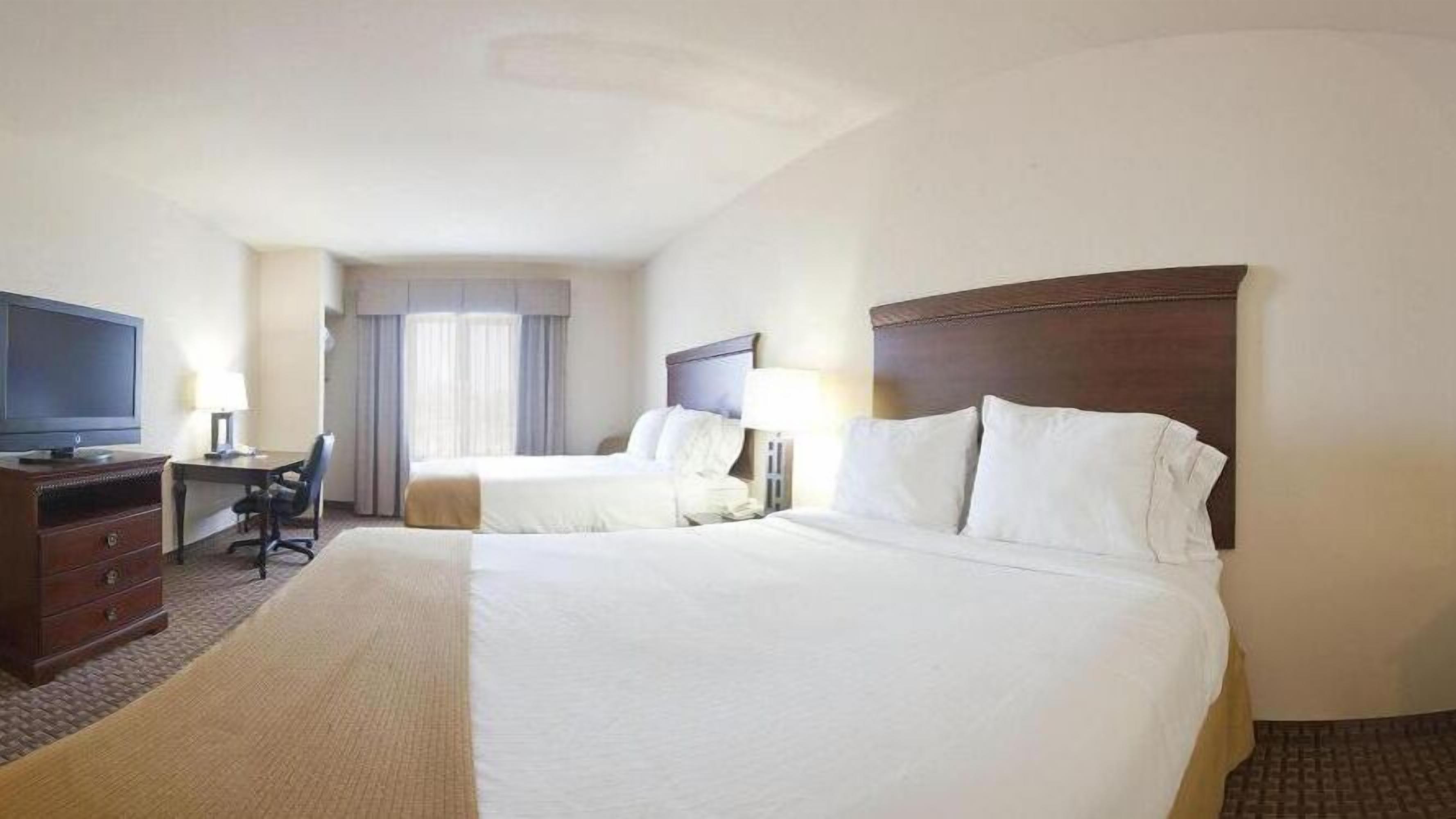 Une chambre d’hôtel avec deux lits, un bureau, une télévision et une chaise.