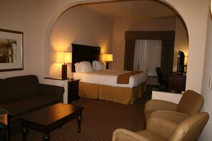 A hotel room with a bed, two bedside lamps, a sofa, a chair, and a desk with a computer. - Holiday Inn Express & Suites Kingsville by IHG (Kingsville)