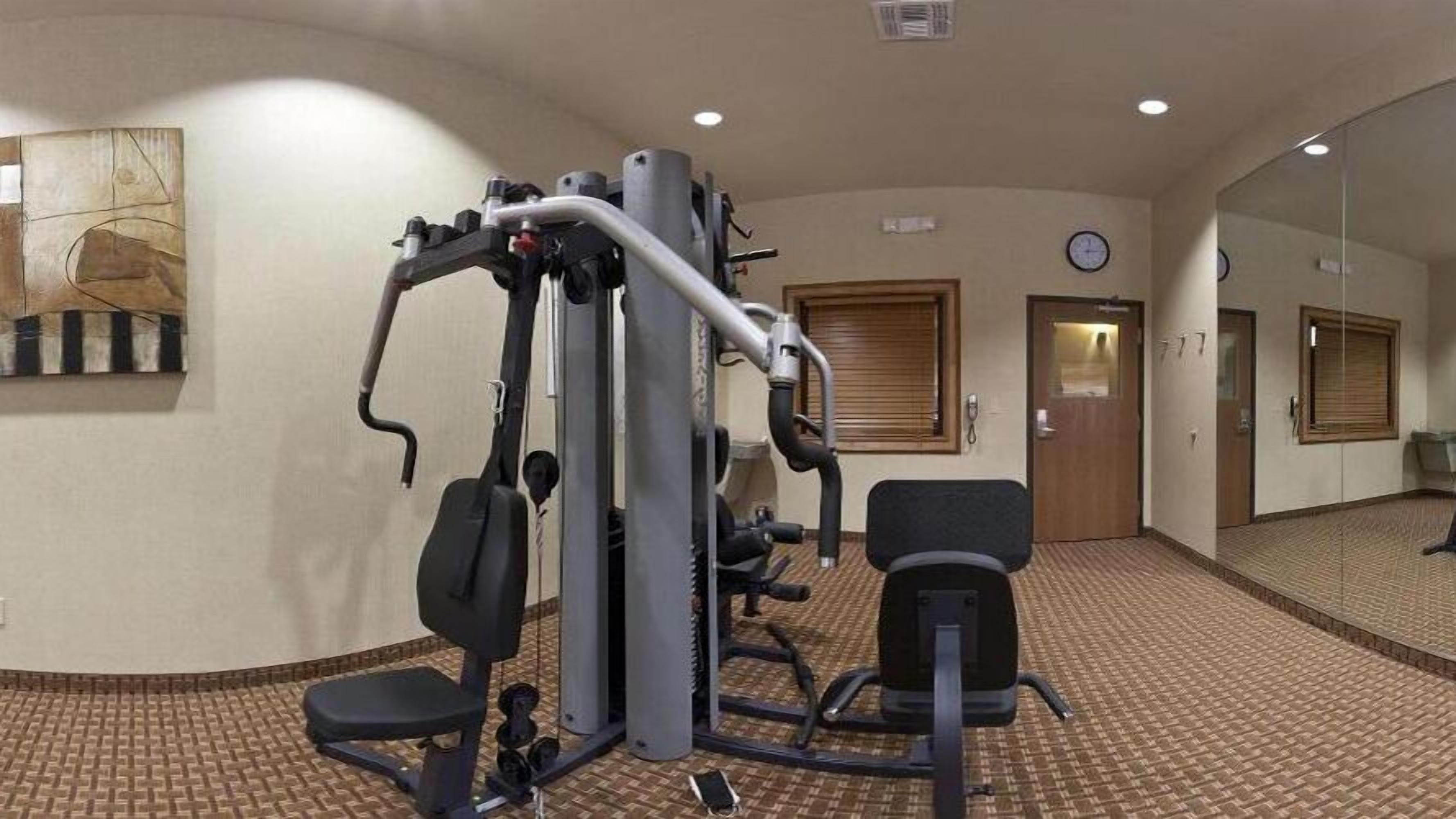 A hotel fitness center with exercise equipment, a clock, and a door.