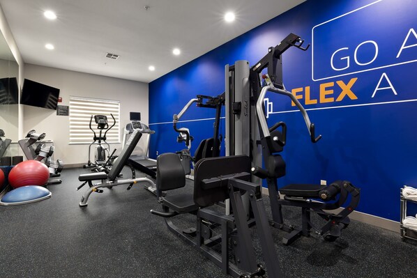 A gym with exercise equipment, a blue wall with motivational text, and a television on the wall. - Holiday Inn Express & Suites Kingsville by IHG (Kingsville)