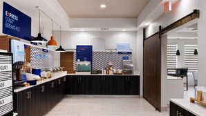 A modern breakfast area with a counter displaying various food items and a sign indicating breakfast is available. - Holiday Inn Express & Suites Kingsville by IHG (Kingsville)