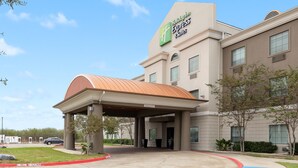 A Holiday Inn Express & Suites building with a covered entrance, a parking lot, and a clear sky. - Holiday Inn Express & Suites Kingsville by IHG (Kingsville)