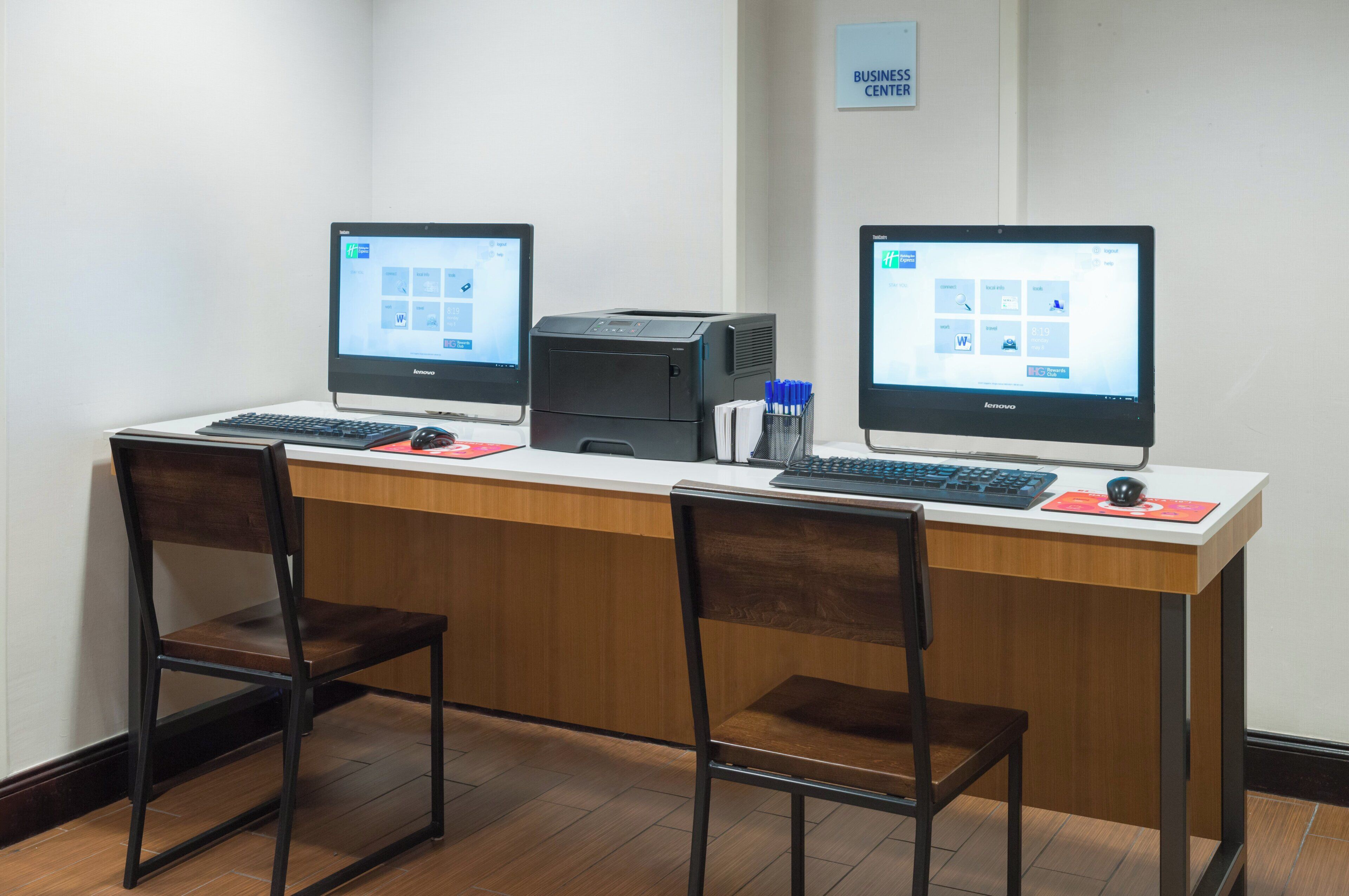 Et forretningscenter med to computerdesk, en printer og to stole.