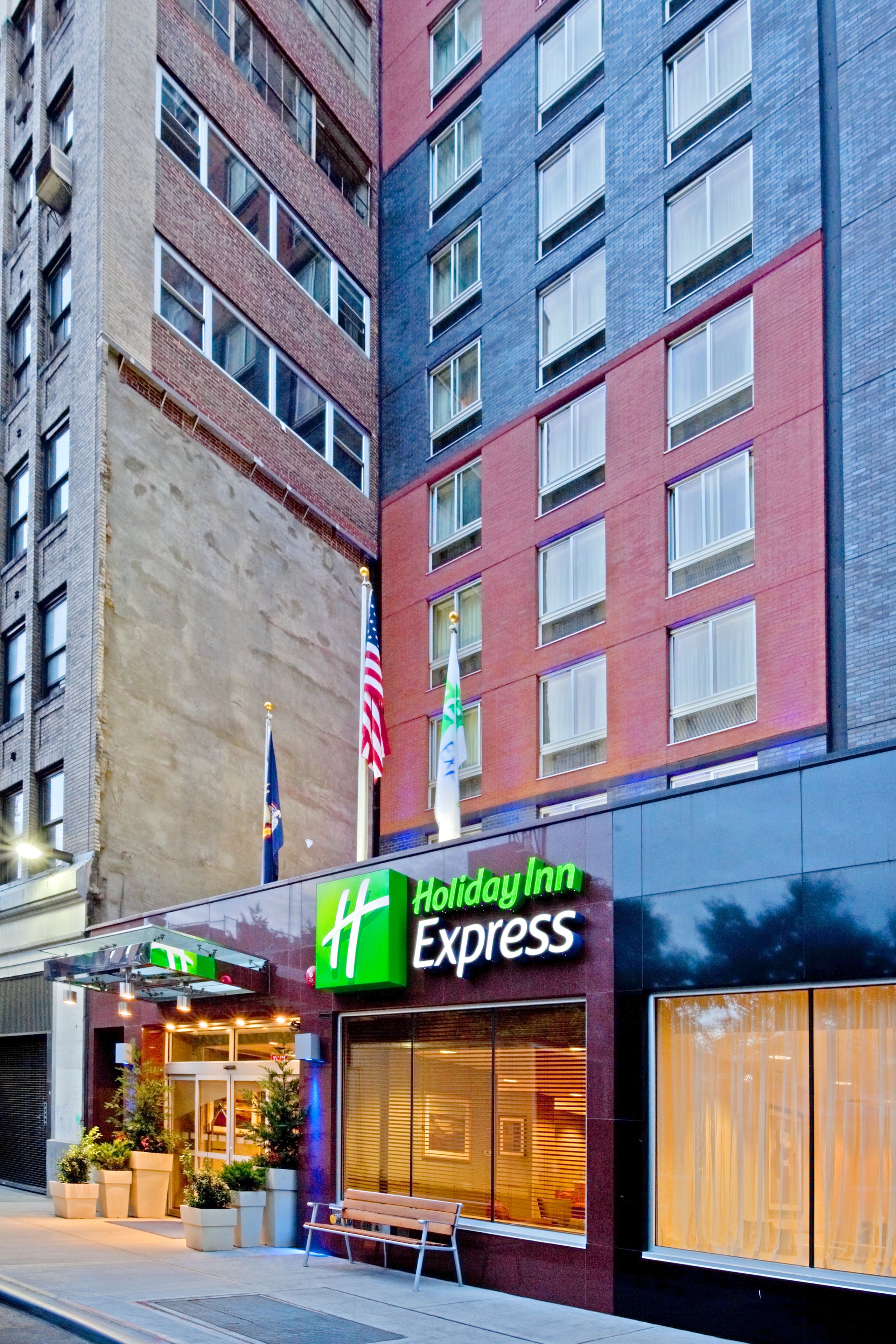 A Holiday Inn Express building with a brick facade, large windows, and a visible American flag.